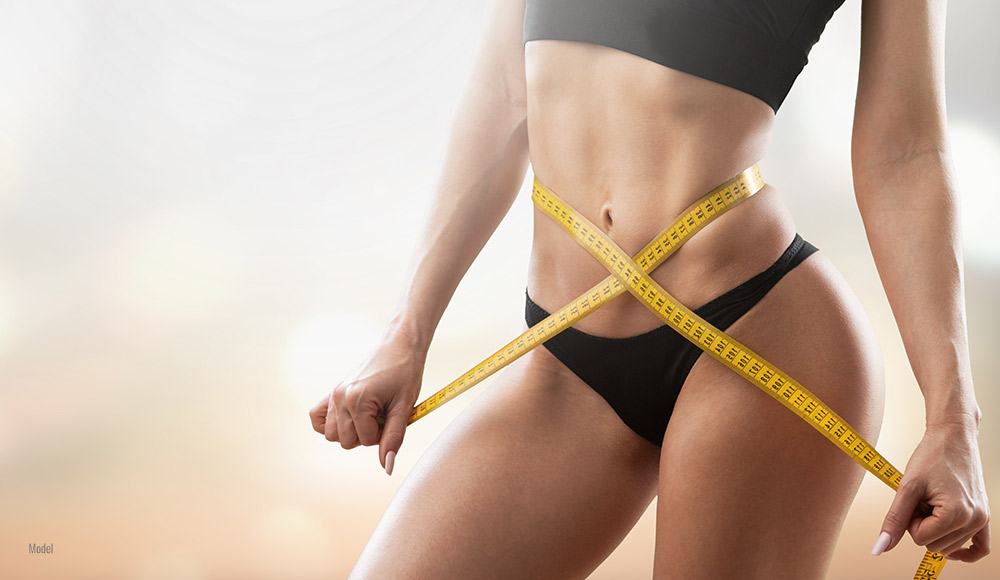 Female with measuring tape over her stomach 