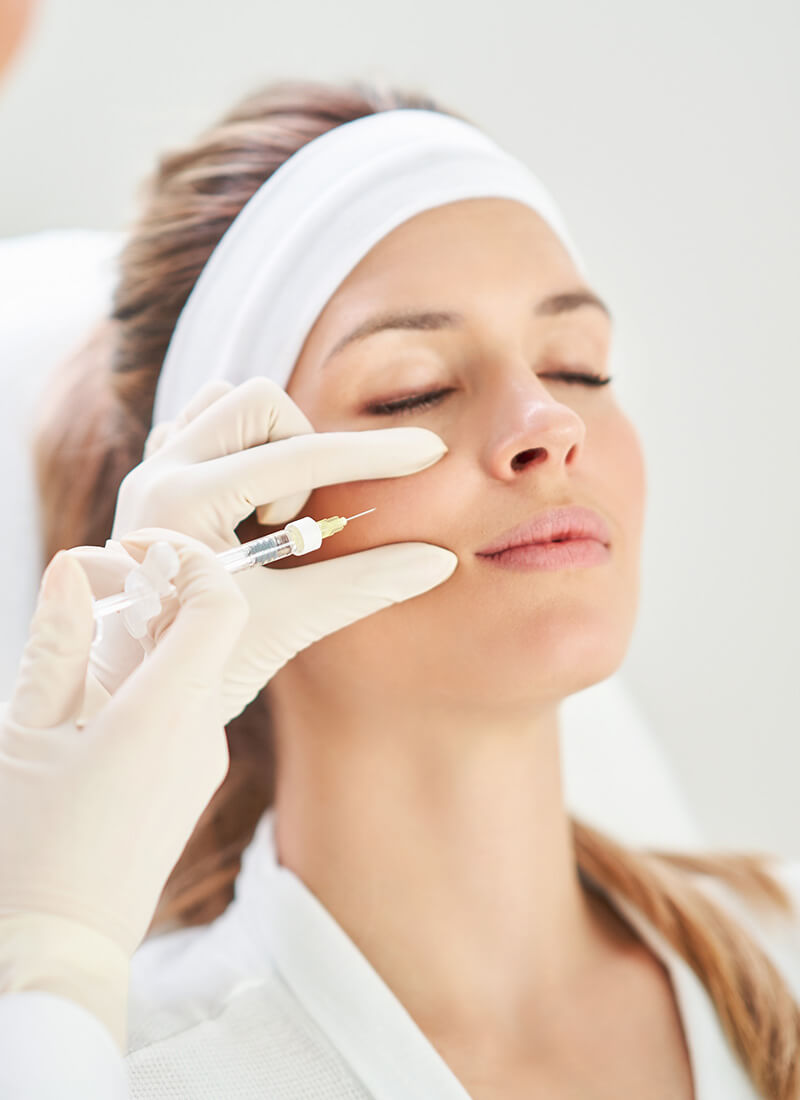 A woman is getting an injection in her face. The procedure is being performed by a doctor.