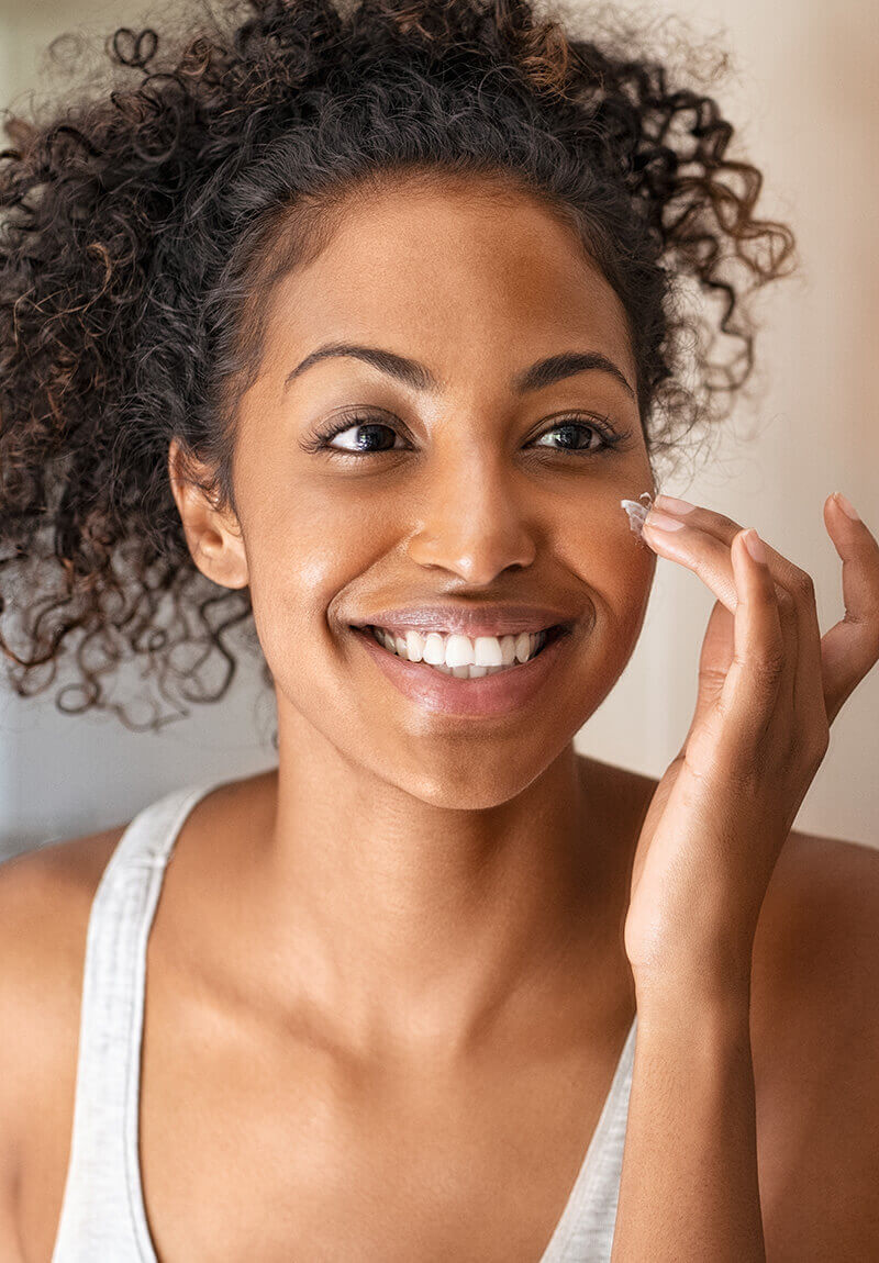 Woman putting cream on her face